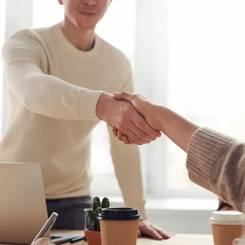 Two people shaking hands over a desk